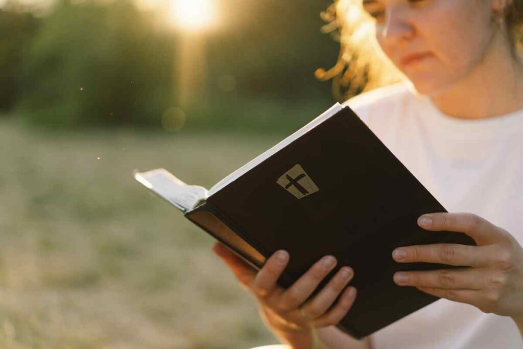 A girl reads the bible during sunset.